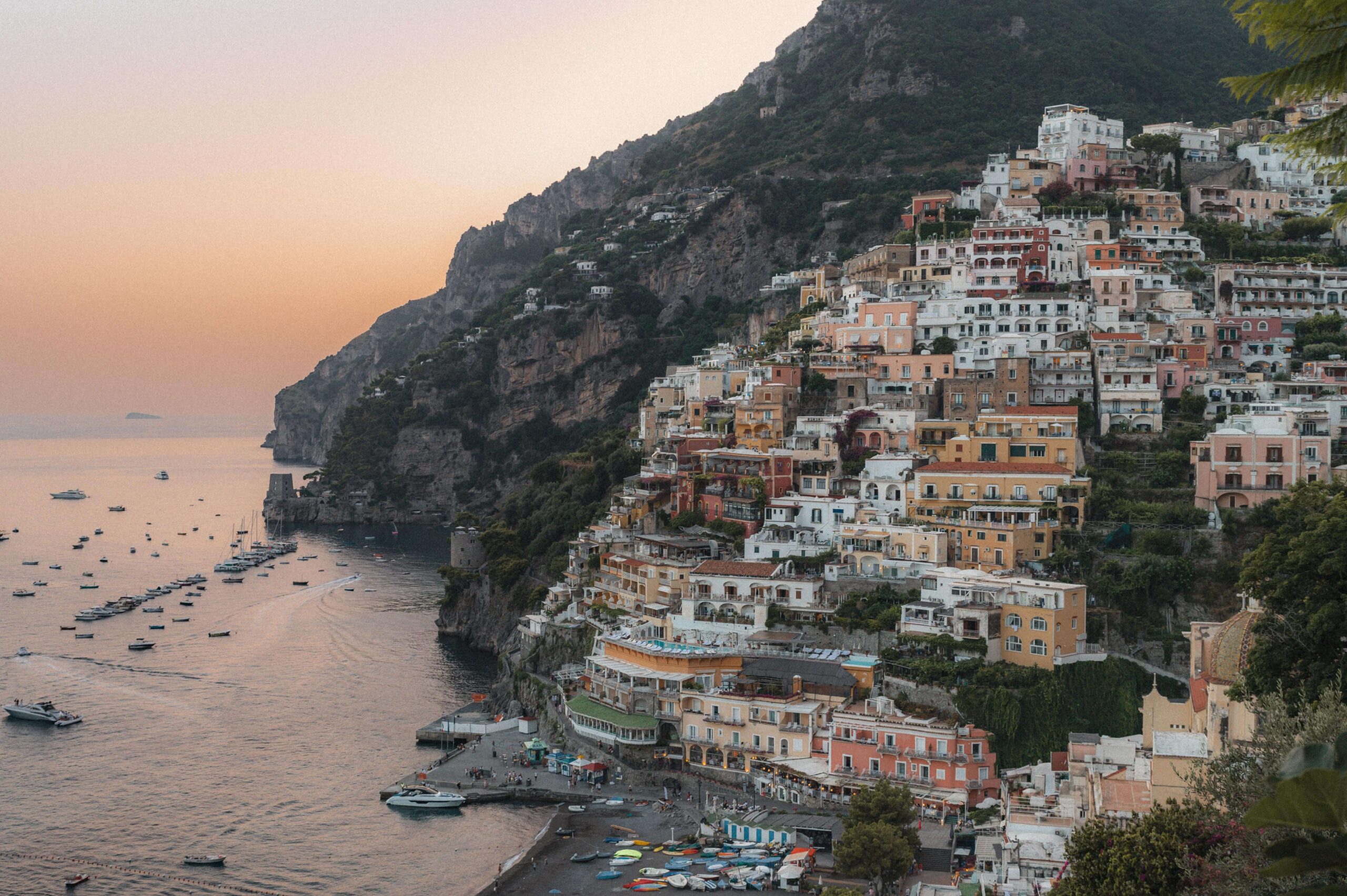 A scenic view of Positano's colourful cliffside buildings overlooking the Mediterranean Sea at sunset