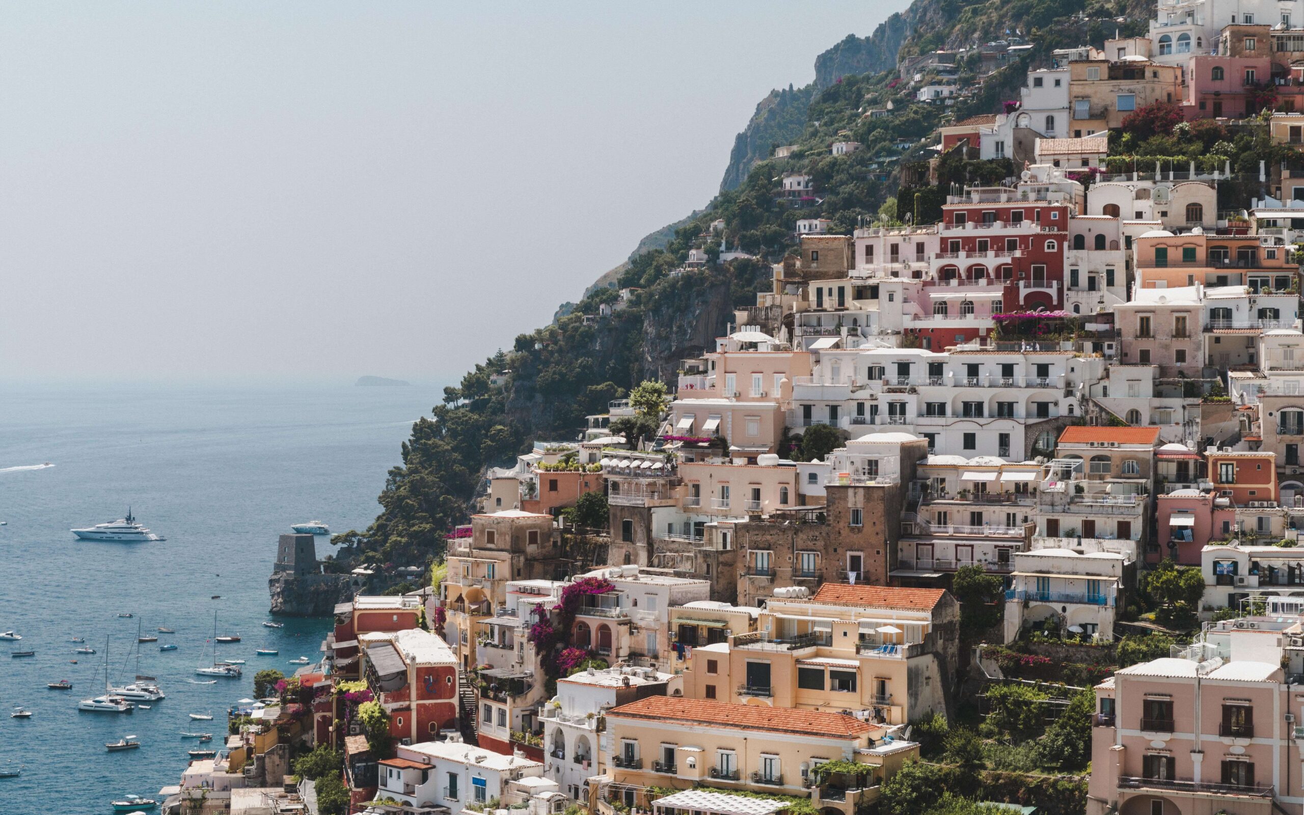 A scenic view of Positano's iconic pastel coloured buildings seemingly cascading down dramatic cliffs of Italy's Amalfi Coast